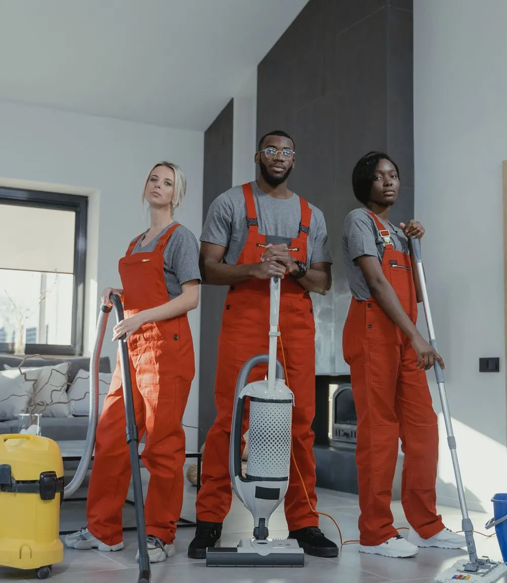 Three cleaning professionals with their equipment in a modern home