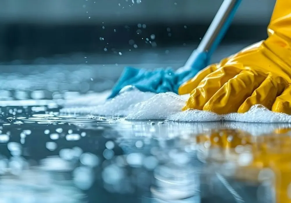 Gloved hands scrubbing a floor during a deep clean